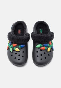 Črne klompe z mehkim črnim flis ovratnikom, ki vsebujejo pisane okraske v obliki žarnic v zeleni, rdeči, modri in rumeni barvi. Prisutne so ventilacijske luknje.