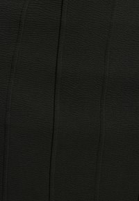 Tissu noir texturé avec un motif de vagues subtil. Le matériau semble doux et léger, avec des lignes de couture verticales pour plus de détail.