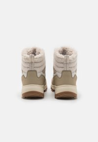 Beige vinterstøvler med en luksuriøs, lysfarget pelskrage, gummisåler og teksturerte paneler på sidene. Bakre trekkremmer for enkel påkledning.