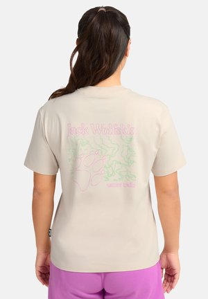 Beiges Baumwoll-T-Shirt mit einem pinken Pfotenabdruck und grünen grafischen Mustern auf der Rückseite, darüber der Schriftzug "Jack Wolfskin". Kurzärmeliges Design.