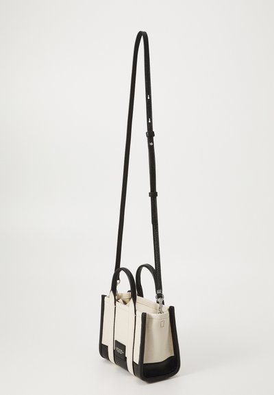 Small handbag featuring a textured black leather base with white upper section and dual handles. Includes a long adjustable strap.