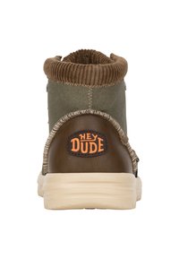 Stivale in tessuto verde con colletto rigato marrone, dettagli in pelle marrone e suola in gomma crema. Presenta il logo "HEY DUDE" sul tallone.