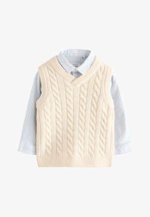 Gilet senza maniche lavorato a trecce color crema, indossato sopra una camicia a righe azzurra e bianca con colletto e maniche lunghe.
