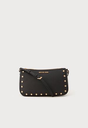 Sac bandoulière en cuir noir avec des clous dorés sur les bords, une fermeture zippée et une bandoulière amovible. Logo affiché à l'avant.
