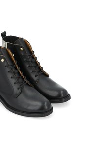 Bottines en cuir noir avec bouts ronds, lacets à l'avant et œillets dorés. Elles présentent un intérieur beige et des détails de couture subtils.
