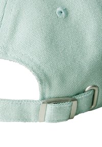 Gorra verde menta clara hecha de tejido texturizado que cuenta con una hebilla de ajuste de metal en la parte posterior y un agujero de ventilación cosido.