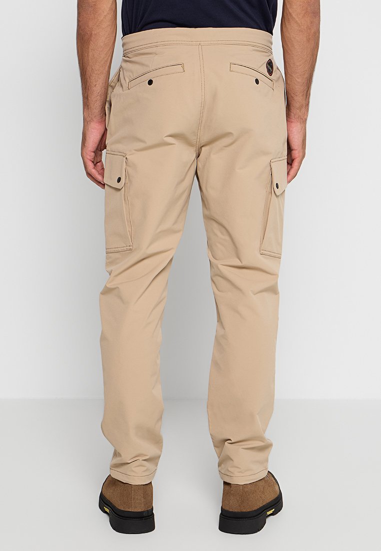 Pantaloni cargo beige con doppie tasche laterali, tasche posteriori e design aderente. Realizzati in un tessuto morbido e resistente con dettagli di cucitura minimi.