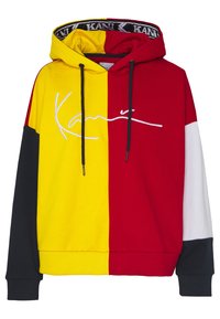 Sweat à capuche avec devant bicolore jaune et rouge, manches noires et blanches, cordons noirs et logo blanc en cursive sur la poitrine.