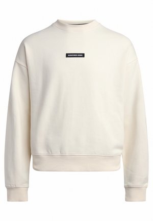 Pulover s krojem crewneck iz kremaste tkanine z mehko teksturo. Vsebuje črn oznako "REDEFINED REBEL" na prsih in rebraste manšete.