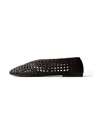 Black woven flat shoe with pointed toe and solid heel section, displayed against a white background in side profile.