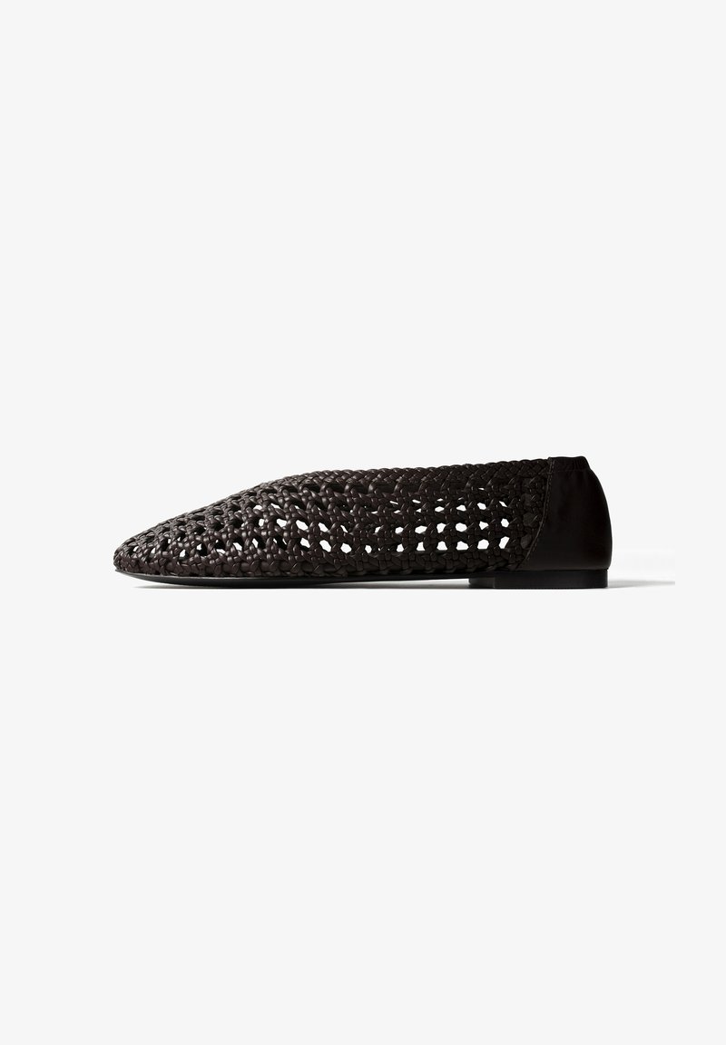 Chaussure plate tissée noire avec bout pointu et section de talon solide, présentée sur un fond blanc en profil latéral.