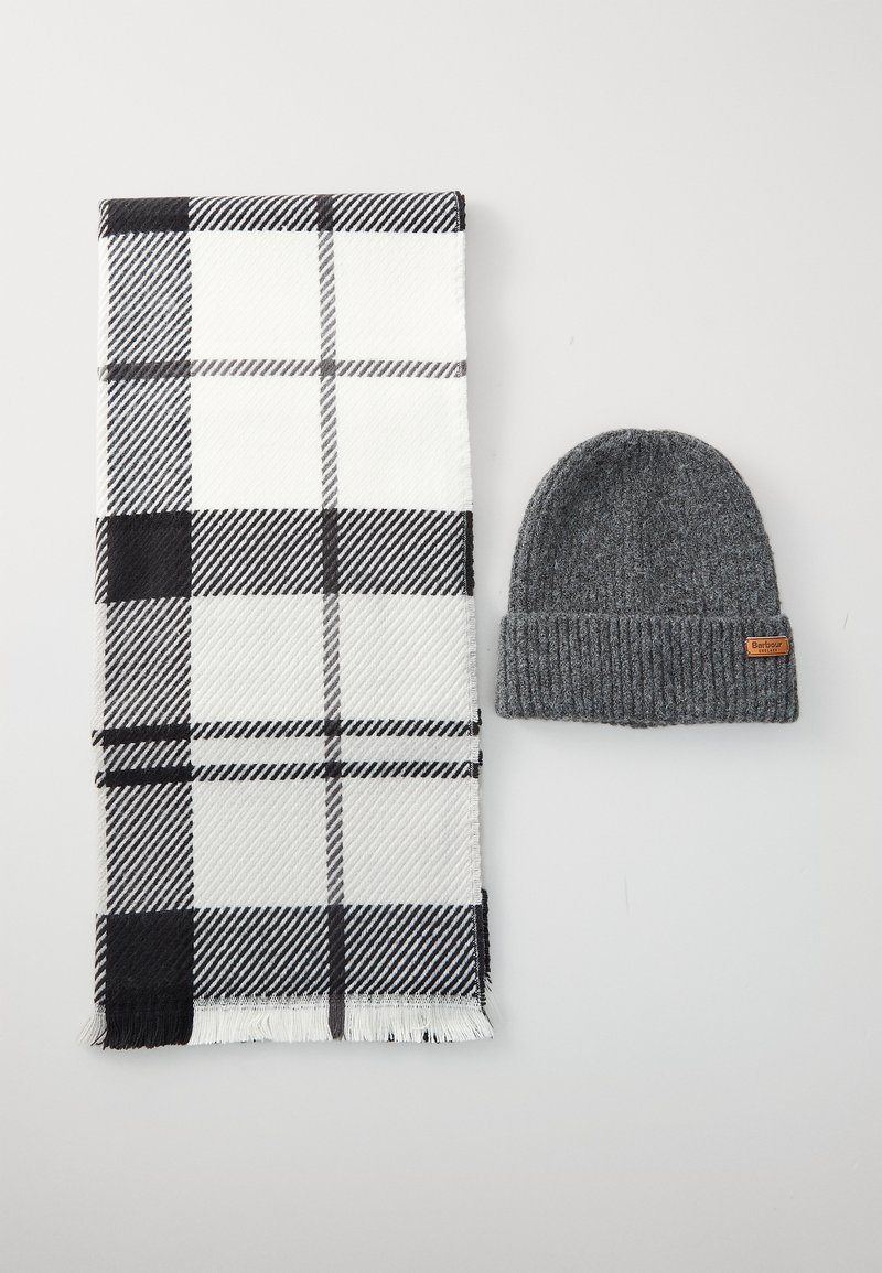 Cachecol xadrez preto e branco com extremidades franjadas, combinado com um gorro de malha cinza escuro, apresentando um pequeno rótulo marrom.