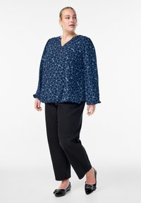 Navy blouse with light blue floral pattern, V-neckline, and long sleeves, paired with black pants and black shoes with embellishments.