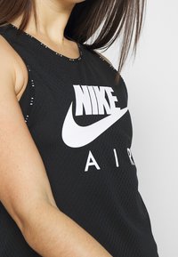 Camiseta sin mangas negra de Nike con tejido texturizado, que presenta grandes logotipos blancos de "NIKE" y "AIR" en la parte frontal.