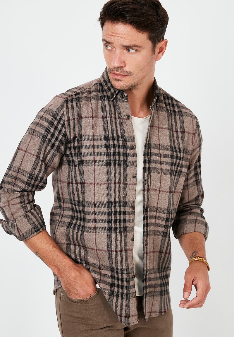Bruine geruite flanellen shirt met zwarte en rode strepen. Heeft een button-down kraag en opgerolde mouwen. Zacht aanvoelend, reguliere pasvorm.