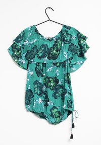 Blusa floreale verde con maniche corte arricciate, dotata di un cordino nero regolabile con nappine all'orlo e una scollatura ampia.