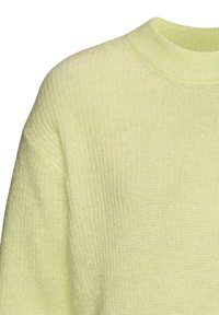 Strickpullover in sanftem Pastellgelb mit Rundhalsausschnitt und Rippstruktur, die Komfort und Wärme im Design betont.