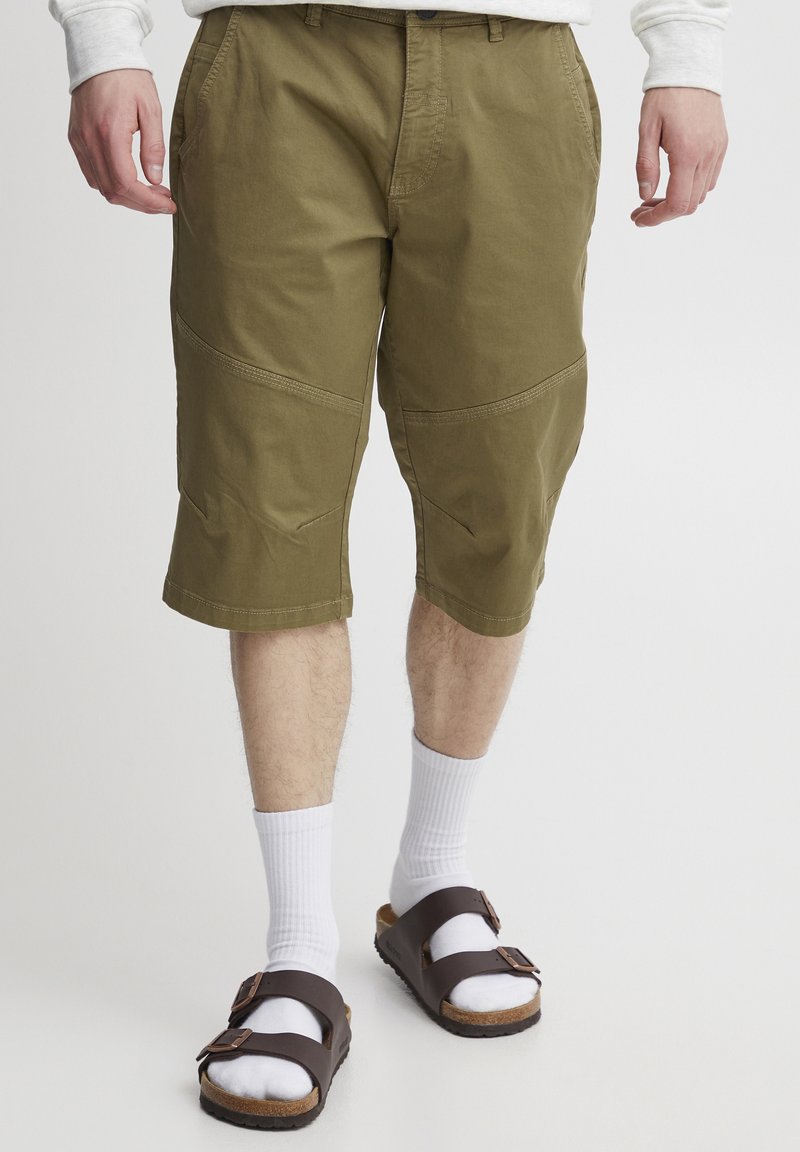 Shorts cargo kaki avec des détails de panneaux latéraux, en coton, avec des accents cousus et une coupe décontractée. Associés à des chaussettes blanches et des sandales brunes.