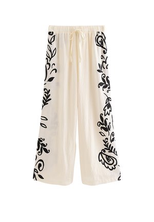 Pantalones blancos de pierna ancha con estampados florales negros a lo largo de los lados exteriores y una cintura elástica con cordón delantero.