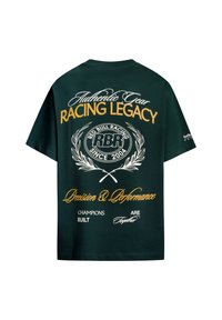Μαύρο T-shirt με κίτρινο και λευκό κείμενο και λογότυπο με θέμα τους αγώνες, συμπεριλαμβανομένων των "Racing Legacy," "Red Bull Racing," και "Precision & Performance."