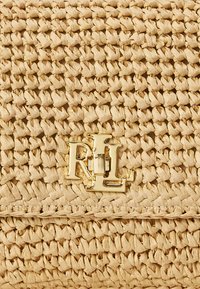 Υφή από μπεζ πλεκτό άχυρο με επικαλυπτόμενο χρυσό μεταλλικό μονόγραμμα που περιλαμβάνει τα γράμματα R, L και H.