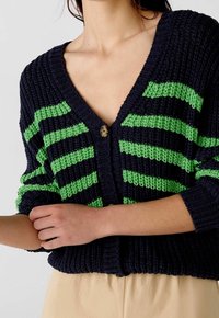 Pruhovaný modro-zelený pletený svetr na zapínání s výstřihem do V, se zapínáním na knoflíky a texturovanou látkou; volné rukávy.