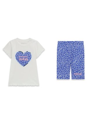 Weißes kurzärmeliges Kleinkind-Shirt mit blauem Blumenherz und dem Text "Move with Guess", kombiniert mit blauen, knielangen Shorts mit Blumenmuster.