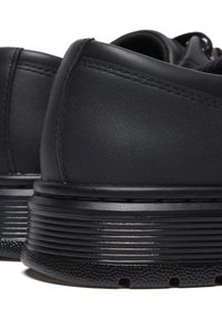 Scarpe in pelle nera con finitura liscia, forma arrotondata e suole in gomma rigata con piccoli fori di drenaggio per il passaggio dell'aria.