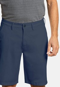 Pantalones cortos azul marino de tela suave con frente plano, cierre de botón, dos bolsillos laterales y un corte recto justo por encima de la rodilla.