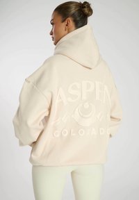 Felpa over-size beige chiaro con una grafica testurizzata "ASPEN COLORADO", caratterizzata da design di montagne e cappuccio con cordino.