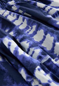 Plava i bijela tkanina sa uzorkom koja ima efekat tie-dye. Mekana tekstura s slojevima, koja prikazuje kombinaciju hrabrih i suptilnih oblika u različitim nijansama.