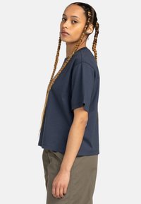 Navy blue cotton t-shirt with a relaxed fit, short sleeves, and a crew neckline, paired with light green cargo pants.