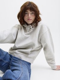 Sweatshirt cinza com capuz, cordão e bolso frontal. Combinado com jeans de ganga azul. Design simples, textura suave, ajuste descontraído.