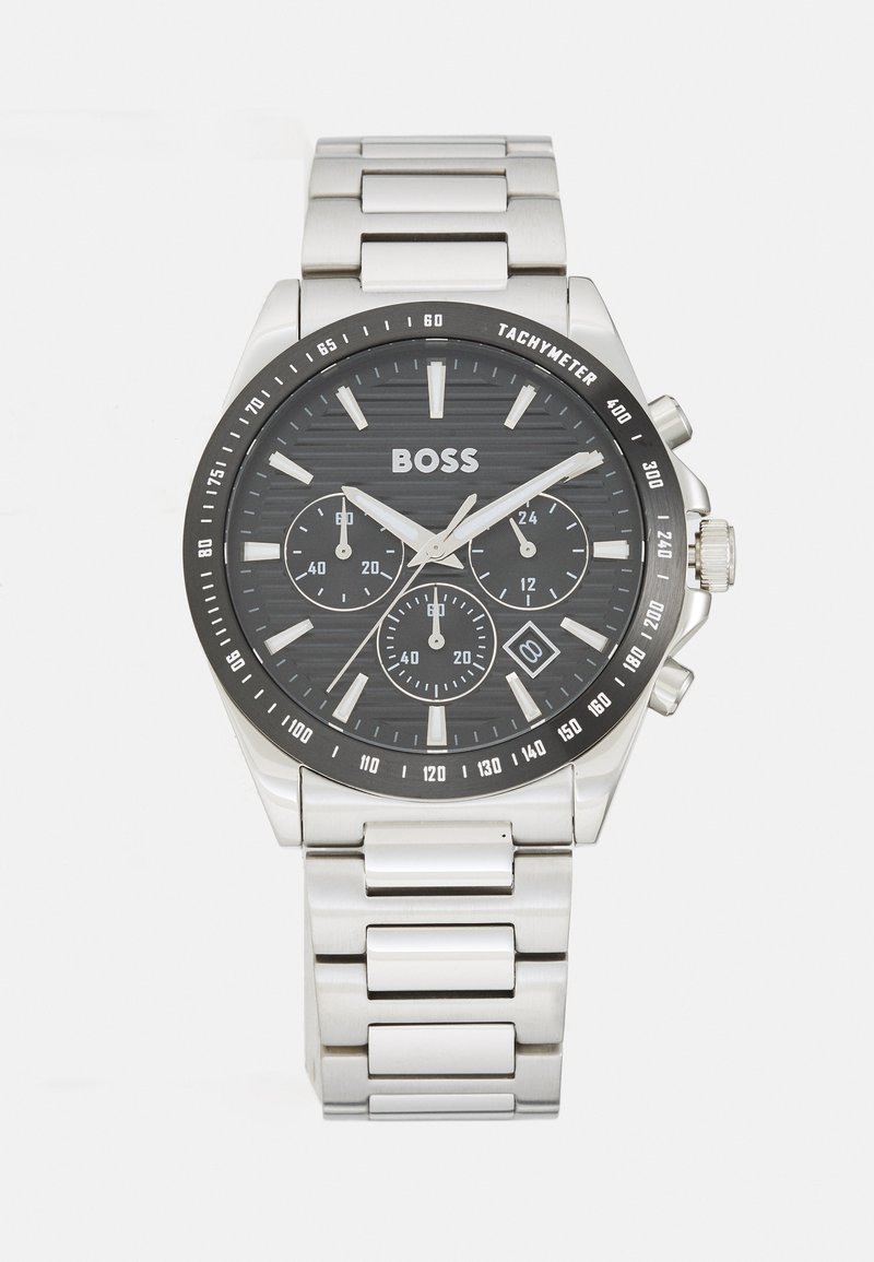 Montre en acier inoxydable BOSS avec un cadran noir texturé, des aiguilles argentées, trois sous-cadrans, une lunette tachymétrique et un bracelet en maillons métalliques.