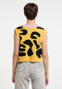 Ærmeløs gul striktop med et iøjnefaldende sort leopardmønster, en kontrasterende lilla kant ved halsen og en cropped længde.
