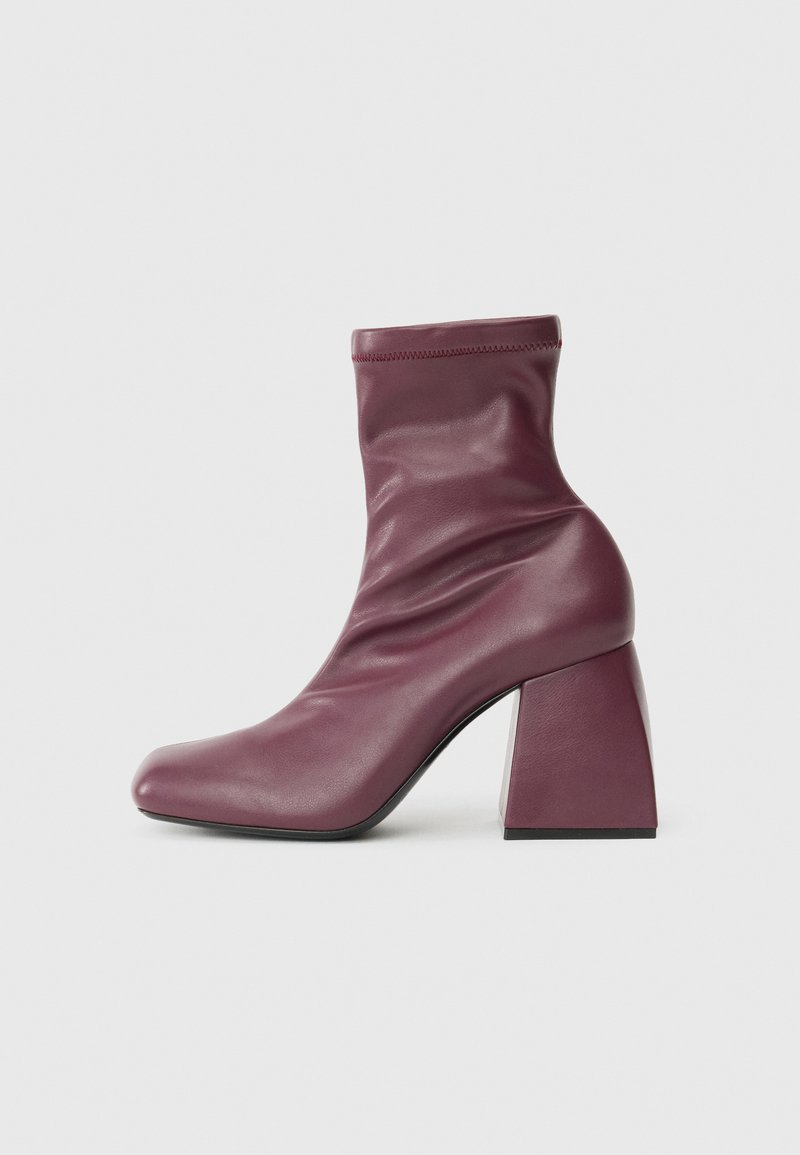 Bottines en cuir bordeaux avec un bout carré effilé, un col élastiqué et un talon géométrique épais. Texture lisse avec un minimum de coutures.