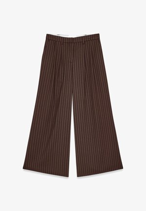 Pantaloni marroni a gamba larga con sottili righe verticali arancioni e passanti per cintura, distesi su uno sfondo bianco.
