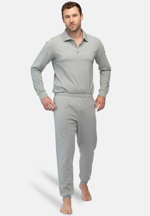 Grijze pyjamaset met lange mouwen, kraag, knopen en elastische broek, gemaakt van zachte stof. Model staat blootvoets tegen een effen achtergrond.