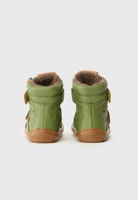 Botas de cuero verde con un suave forro de piel marrón, con correas de velcro y suela de goma. La marca "froddo" está estampada en el talón.
