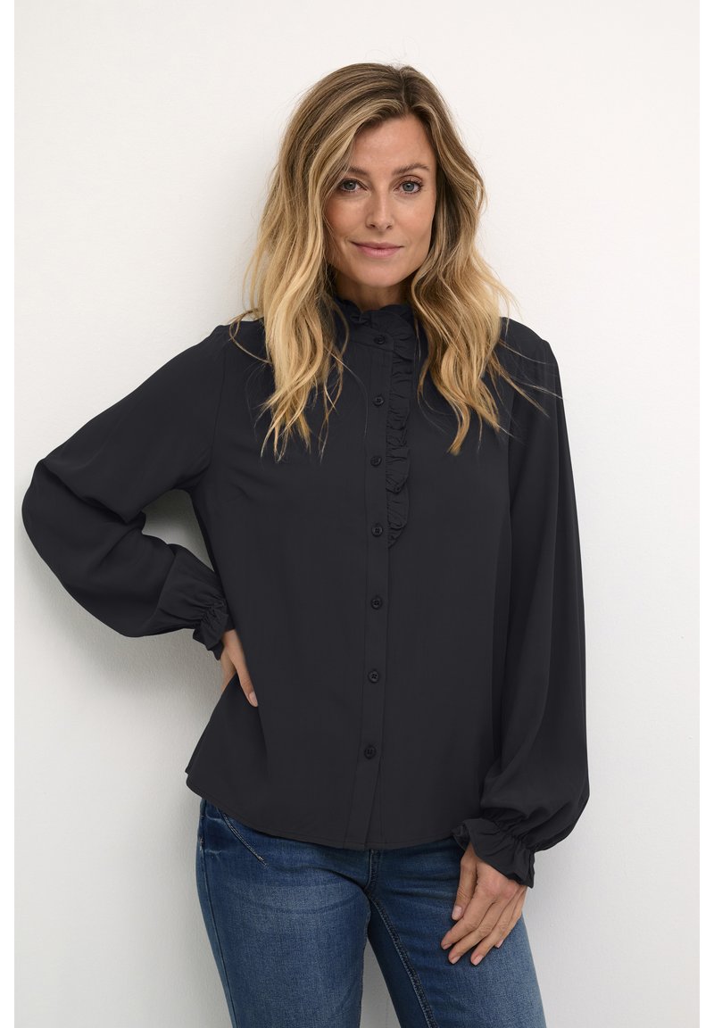Black long-sleeve shirt with a ruffled front, button closure, and gathered cuffs. Paired with blue denim jeans. Soft, lightweight fabric.