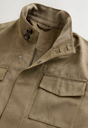 Giacca in suede marrone con colletto alto, due tasche frontali e chiusura con zip. Il tessuto ha una finitura morbida e texturizzata.