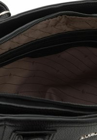 Schwarze, strukturierte Handtasche mit einem Reißverschluss; das Innere ist mit einem glatten braunen Futter mit subtilen diagonalen Mustern ausgestattet.