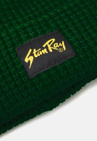 Roheline kootud müts tekstuuriga mustriga. Omab musta kangast silti, millel on kollane "Stan Ray" logo õmmelduna ühelt küljelt.
