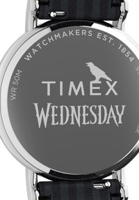 Must musta mustra, mustra ja halli kell, millel on ümmargune nägu, hõbedased elemendid ja triibuline kangastrap. Näitab rasvaste tähtedega "TIMEX" ja "KOLMAPÄEV".