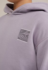 Levanduľová mikina s kapucňou, s malou grafiku s čiernymi líniami a textom, vyrobená z jemného materiálu, s uvoľneným strihom a šnúrkou na kapucni.