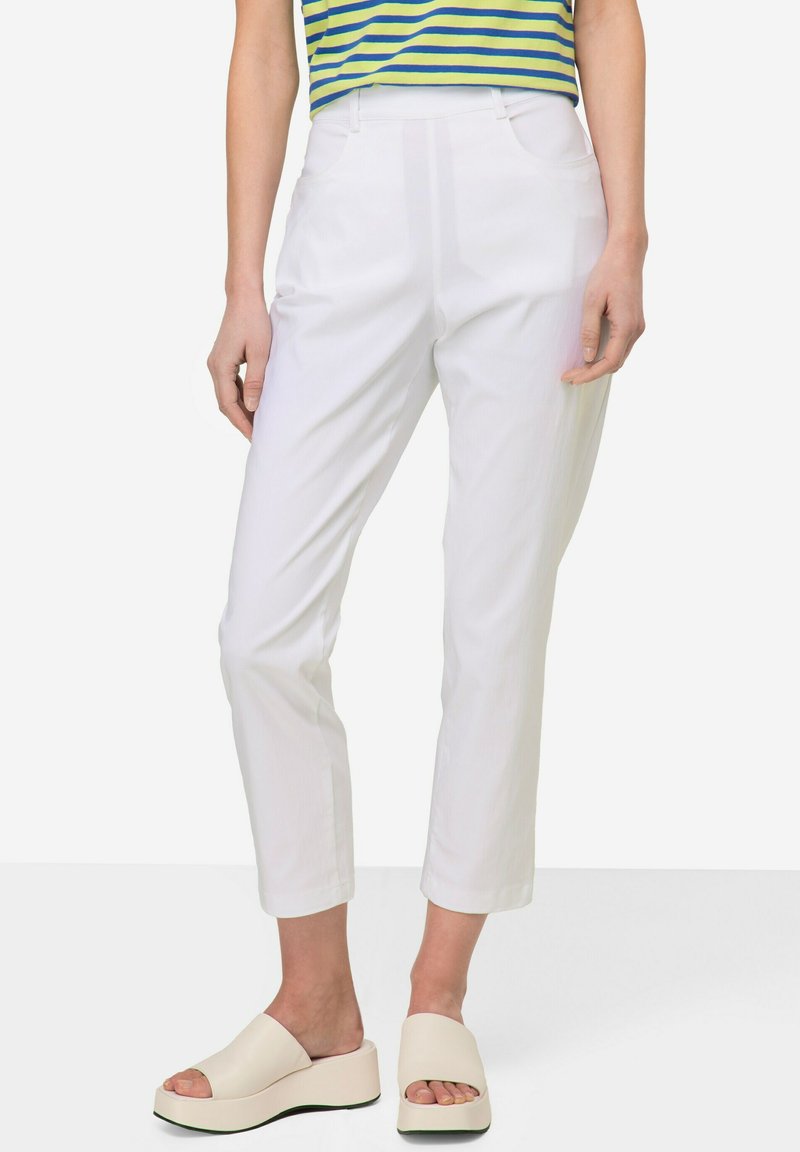 Pantalons blancs ajustés avec une jambe droite, dotés de poches avant, associés à des sandales à plateforme beige clair, portés avec un haut rayé.