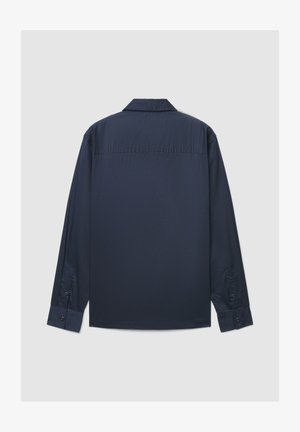 Chemise bleu marine à manches longues avec un col classique, une texture lisse, des poignets avec boutons et un ourlet droit. Présente un design arrière épuré et minimaliste.