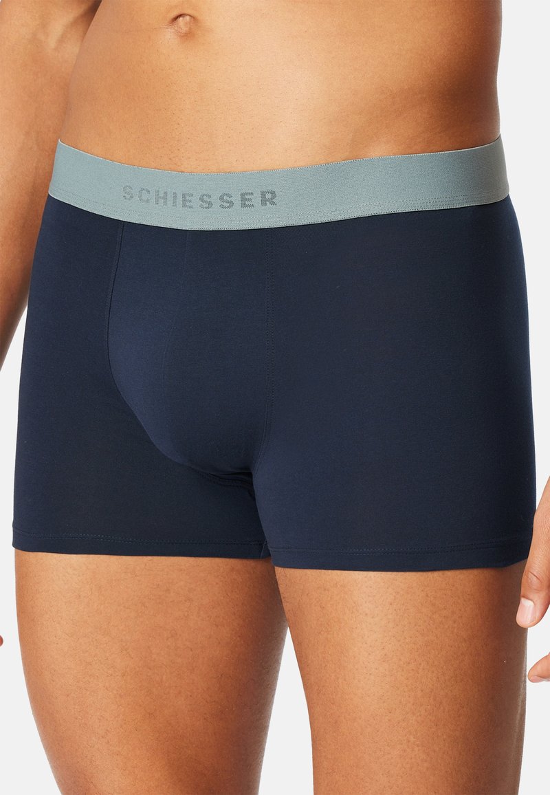 Boxer blu navy con una morbida fascia in vita grigio chiaro con il logo "SCHIESSER" in rilievo. Realizzati in tessuto liscio e elasticizzato.