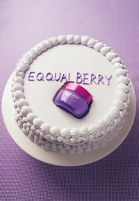 Białe ciasto pokryte fioletowym lukrem, z napisem "EQUALBERRY" napisanym fioletowym lukrem. Na wierzchu umieszczony jest fioletowy słoik z różową pokrywką.