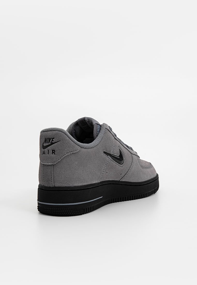 Zapatillas de ante gris con suela de goma negra, con un diseño curvado, cuello acolchado y un prominente logo de swoosh negro de Nike en el lateral.